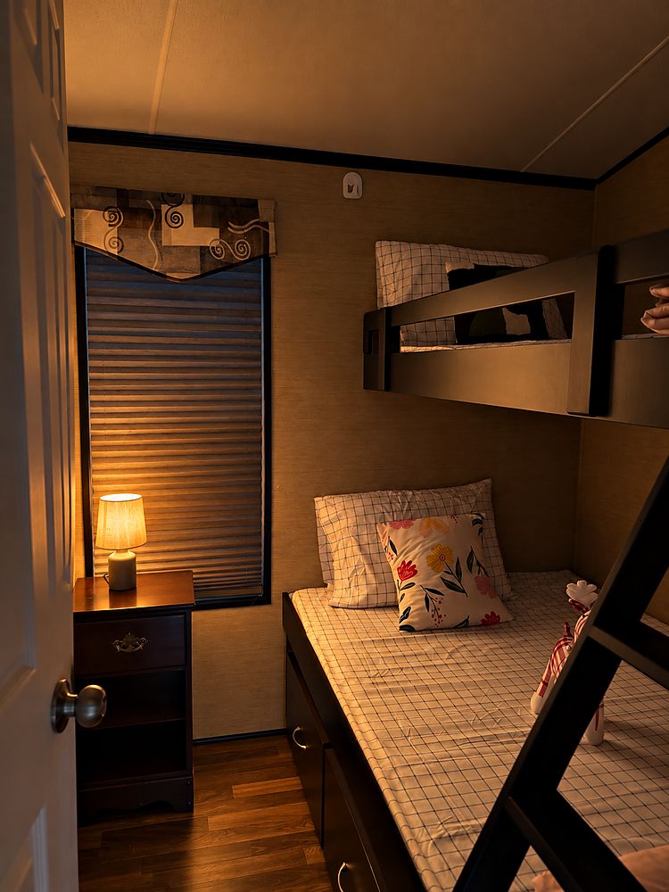 The bunk room at Peacedale Cottage, made up with fresh linen and a bedside lamp lit