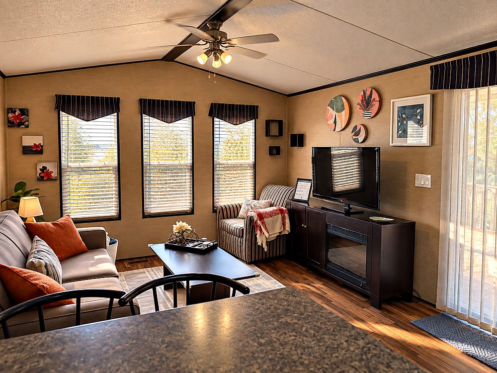 Peacedale Cottage living area with an armchair, television and electric fireplace beside the patio doors