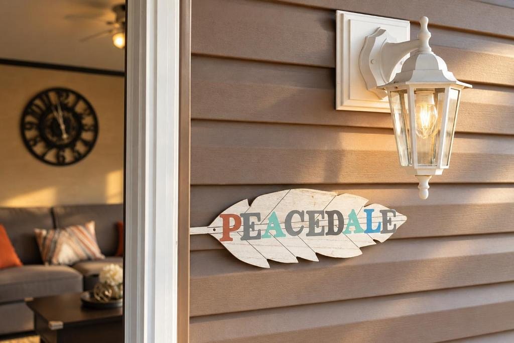 The hand-painted Peacedale feather sign on the siding beside the porch lantern